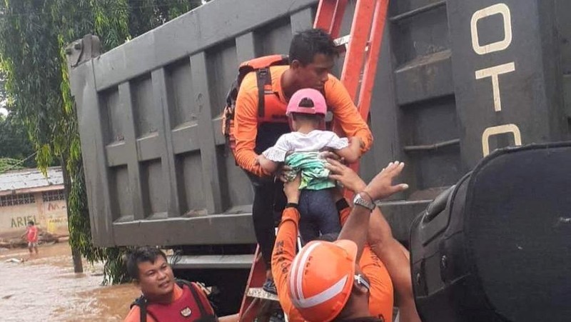 Petugas penyelamat membantu korban banjir di Plaridel, Misamis Occidental Province, Filipina, (26/12/2022). (via REUTERS/PHILIPPINE COAST GUARD)