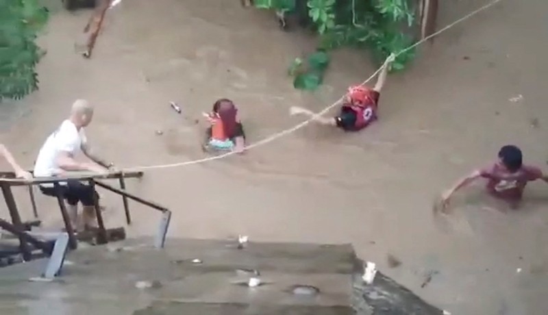 Petugas penyelamat membantu korban banjir di Plaridel, Misamis Occidental Province, Filipina, (26/12/2022). (via REUTERS/PHILIPPINE COAST GUARD)