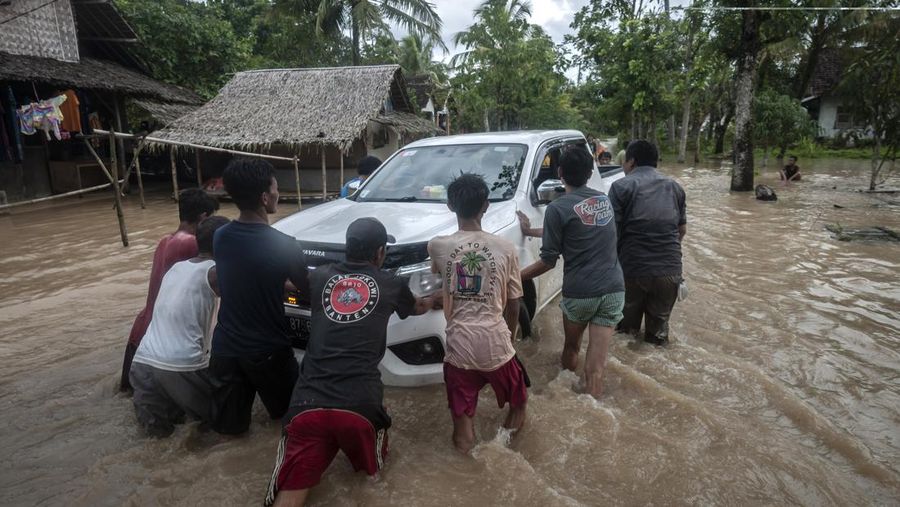 Warga mendorong mobil yang mogok saat banjir menggenangi kawasan Patia, Pandeglang, Banten, Selasa (27/12/2022). BPBD Kabupaten Pandeglang mencatat sebanyak 728 rumah di tiga kecamatan Pandeglang terendam banjir sejak hari Minggu (25/12/2022) dan hingga Selasa (27/12) banjir masih menggenangi kawasan tersebut. ANTARA FOTO/Muhammad Bagus Khoirunas/aww.