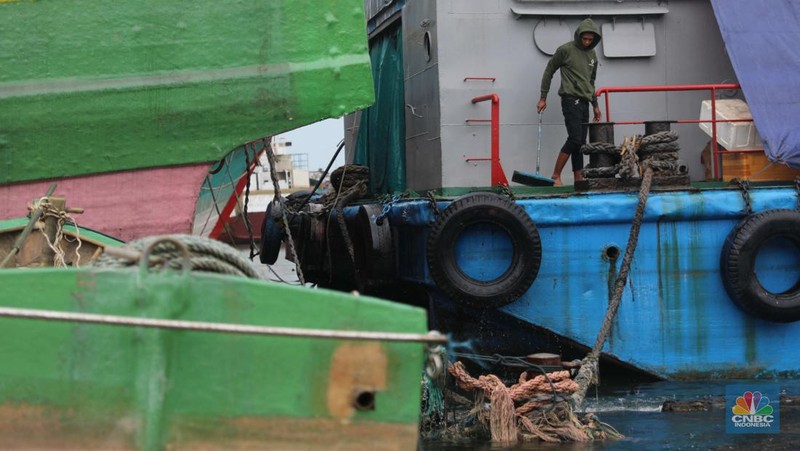 Anak Buah Kapal (ABK) melintasi banjir rob saat cuaca buruk di Pelabuhan Muara Baru, Penjaringan, Jakarta Utara, Rabu (28/12/2022). Badan Meteorologi Klimatologi dan Geofisika (BMKG) menyampaikan ada potensi cuaca ekstrem terjadi di sejumlah wilayah di Indonesia. (վ/ Muhammad Sabki)