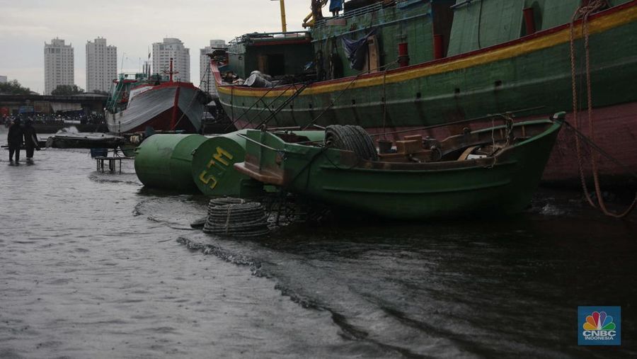 Anak Buah Kapal (ABK) melintasi banjir rob saat cuaca buruk di Pelabuhan Muara Baru, Penjaringan, Jakarta Utara, Rabu (28/12/2022). Badan Meteorologi Klimatologi dan Geofisika (BMKG) menyampaikan ada potensi cuaca ekstrem terjadi di sejumlah wilayah di Indonesia. (CNBC Indonesia/ Muhammad Sabki)