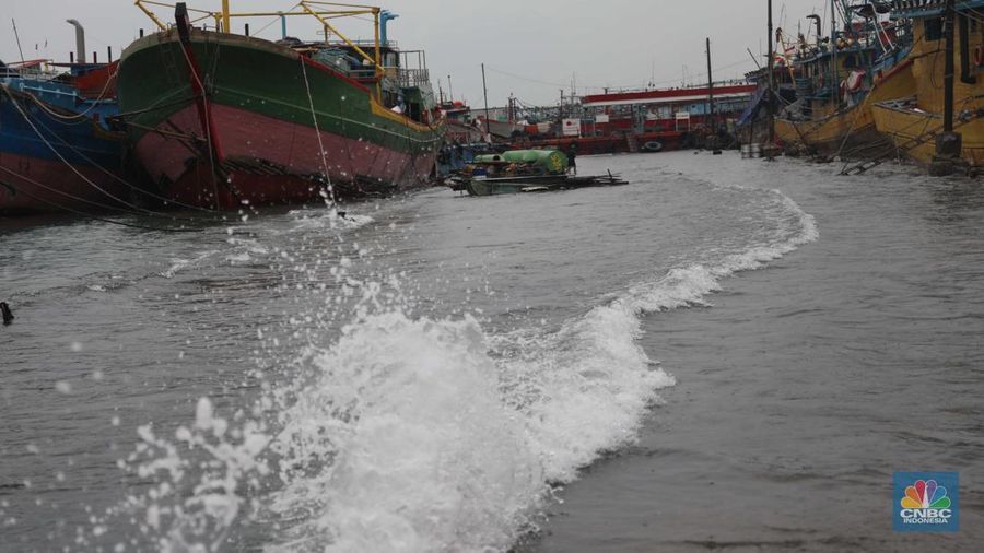 Anak Buah Kapal (ABK) melintasi banjir rob saat cuaca buruk di Pelabuhan Muara Baru, Penjaringan, Jakarta Utara, Rabu (28/12/2022). Badan Meteorologi Klimatologi dan Geofisika (BMKG) menyampaikan ada potensi cuaca ekstrem terjadi di sejumlah wilayah di Indonesia. (CNBC Indonesia/ Muhammad Sabki)