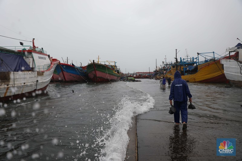 Banjir Rob di Pelabuhan Muara Baru, Anak Buah Kapal (ABK) melintasi banjir rob saat cuaca buruk di Pelabuhan Muara Baru, Penjaringan, Jakarta Utara, Rabu (28/12/2022). Badan Meteorologi Klimatologi dan Geofisika (BMKG) menyampaikan ada potensi cuaca ekstrem terjadi di sejumlah wilayah di Indonesia. (CNBC Indonesia/ Muhammad Sabki)