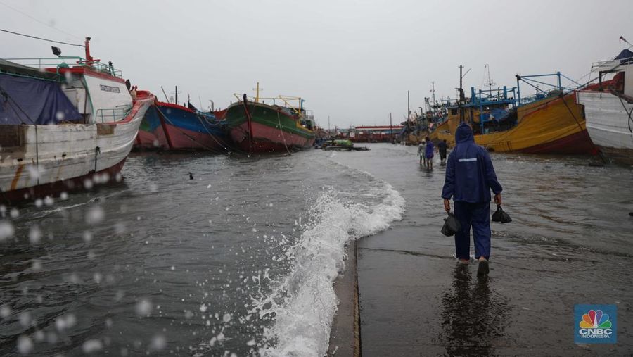 Anak Buah Kapal (ABK) melintasi banjir rob saat cuaca buruk di Pelabuhan Muara Baru, Penjaringan, Jakarta Utara, Rabu (28/12/2022). Badan Meteorologi Klimatologi dan Geofisika (BMKG) menyampaikan ada potensi cuaca ekstrem terjadi di sejumlah wilayah di Indonesia. (վ/ Muhammad Sabki)