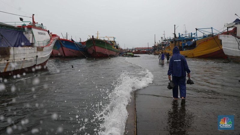 Anak Buah Kapal (ABK) melintasi banjir rob saat cuaca buruk di Pelabuhan Muara Baru, Penjaringan, Jakarta Utara, Rabu (28/12/2022). Badan Meteorologi Klimatologi dan Geofisika (BMKG) menyampaikan ada potensi cuaca ekstrem terjadi di sejumlah wilayah di Indonesia. (վ/ Muhammad Sabki)