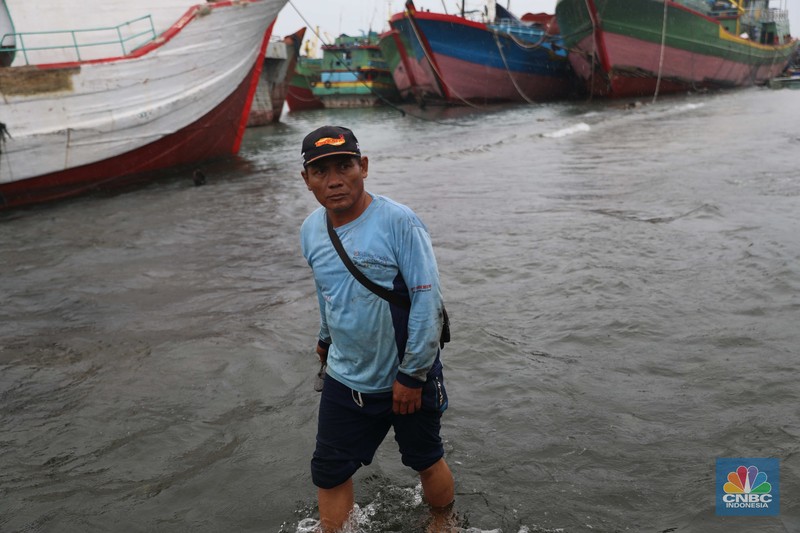Anak Buah Kapal (ABK) melintasi banjir rob saat cuaca buruk di Pelabuhan Muara Baru, Penjaringan, Jakarta Utara, Rabu (28/12/2022). Badan Meteorologi Klimatologi dan Geofisika (BMKG) menyampaikan ada potensi cuaca ekstrem terjadi di sejumlah wilayah di Indonesia. (CNBC Indonesia/ Muhammad Sabki)