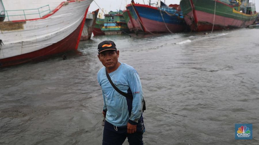 Anak Buah Kapal (ABK) melintasi banjir rob saat cuaca buruk di Pelabuhan Muara Baru, Penjaringan, Jakarta Utara, Rabu (28/12/2022). Badan Meteorologi Klimatologi dan Geofisika (BMKG) menyampaikan ada potensi cuaca ekstrem terjadi di sejumlah wilayah di Indonesia. (վ/ Muhammad Sabki)
