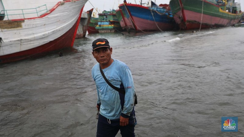 Anak Buah Kapal (ABK) melintasi banjir rob saat cuaca buruk di Pelabuhan Muara Baru, Penjaringan, Jakarta Utara, Rabu (28/12/2022). Badan Meteorologi Klimatologi dan Geofisika (BMKG) menyampaikan ada potensi cuaca ekstrem terjadi di sejumlah wilayah di Indonesia. (վ/ Muhammad Sabki)