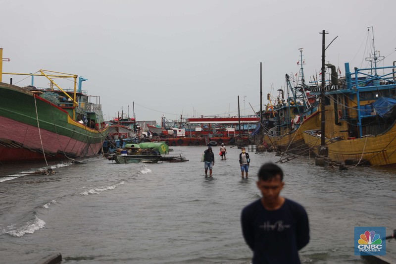Banjir Rob di Pelabuhan Muara Baru, Anak Buah Kapal (ABK) melintasi banjir rob saat cuaca buruk di Pelabuhan Muara Baru, Penjaringan, Jakarta Utara, Rabu (28/12/2022). Badan Meteorologi Klimatologi dan Geofisika (BMKG) menyampaikan ada potensi cuaca ekstrem terjadi di sejumlah wilayah di Indonesia. (CNBC Indonesia/ Muhammad Sabki)