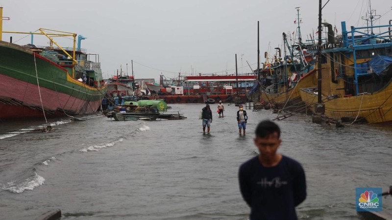 Anak Buah Kapal (ABK) melintasi banjir rob saat cuaca buruk di Pelabuhan Muara Baru, Penjaringan, Jakarta Utara, Rabu (28/12/2022). Badan Meteorologi Klimatologi dan Geofisika (BMKG) menyampaikan ada potensi cuaca ekstrem terjadi di sejumlah wilayah di Indonesia. (վ/ Muhammad Sabki)