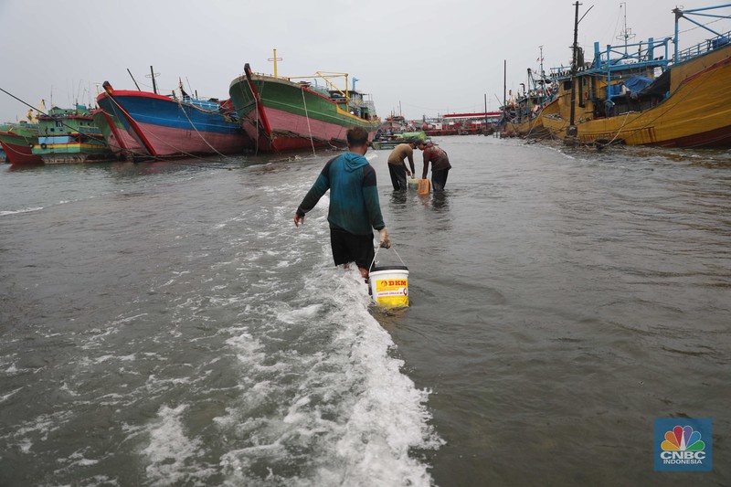 Banjir Rob di Pelabuhan Muara Baru, Anak Buah Kapal (ABK) melintasi banjir rob saat cuaca buruk di Pelabuhan Muara Baru, Penjaringan, Jakarta Utara, Rabu (28/12/2022). Badan Meteorologi Klimatologi dan Geofisika (BMKG) menyampaikan ada potensi cuaca ekstrem terjadi di sejumlah wilayah di Indonesia. (CNBC Indonesia/ Muhammad Sabki)