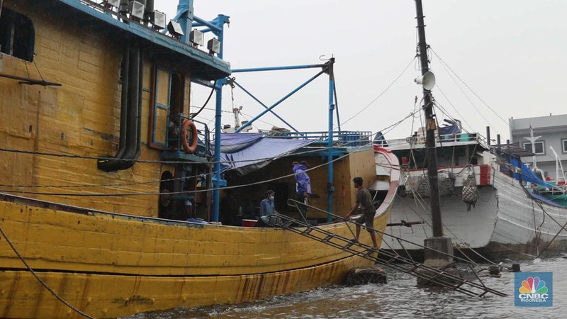 Anak Buah Kapal (ABK) melintasi banjir rob saat cuaca buruk di Pelabuhan Muara Baru, Penjaringan, Jakarta Utara, Rabu (28/12/2022). Badan Meteorologi Klimatologi dan Geofisika (BMKG) menyampaikan ada potensi cuaca ekstrem terjadi di sejumlah wilayah di Indonesia. (վ/ Muhammad Sabki)