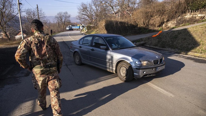 Tentara Italia yang bertugas dalam misi penjaga perdamaian internasional yang dipimpin NATO di Kosovo berpatroli di dekat jalan yang dibarikade dengan truk oleh warga Serbia di desa Rudare dekat kota Zvecan, Kosovo, Senin (26/12/2022).  Sejak November, Kosovo bergejolak usai ratusan pekerja etnis Serbia ramai-ramai mengundurkan diri. Mereka memprotes keputusan kontroversial pemerintah Kosovo yang melarang orang Serbia di negara itu menggunakan plat nomor dari Beograd. (Photo by ARMEND NIMANI/AFP via Getty Images)