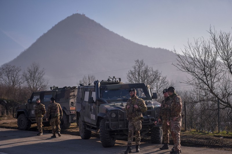Tentara Italia yang bertugas dalam misi penjaga perdamaian internasional yang dipimpin NATO di Kosovo berpatroli di dekat jalan yang dibarikade dengan truk oleh warga Serbia di desa Rudare dekat kota Zvecan, Kosovo, Senin (26/12/2022).  Sejak November, Kosovo bergejolak usai ratusan pekerja etnis Serbia ramai-ramai mengundurkan diri. Mereka memprotes keputusan kontroversial pemerintah Kosovo yang melarang orang Serbia di negara itu menggunakan plat nomor dari Beograd. (Photo by ARMEND NIMANI/AFP via Getty Images)
