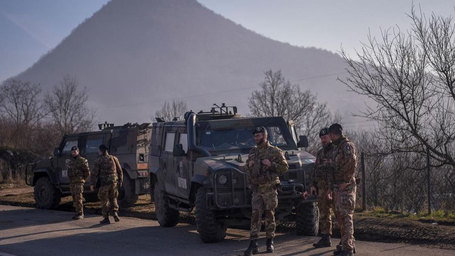 Tentara Italia yang bertugas dalam misi penjaga perdamaian internasional yang dipimpin NATO di Kosovo berpatroli di dekat jalan yang dibarikade dengan truk oleh warga Serbia di desa Rudare dekat kota Zvecan, Kosovo, Senin (26/12/2022). Sejak November, Kosovo bergejolak usai ratusan pekerja etnis Serbia ramai-ramai mengundurkan diri. Mereka memprotes keputusan kontroversial pemerintah Kosovo yang melarang orang Serbia di negara itu menggunakan plat nomor dari Beograd. (Photo by ARMEND NIMANI/AFP via Getty Images)