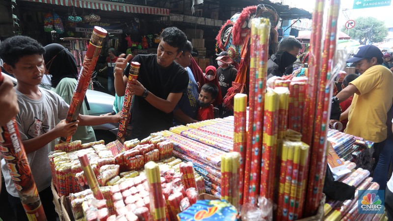 Pedagang melayani pembeli kembang api yang dijual di kawasan pasar Asemka, Jakarta Barat, Jumat (30/12/2022). Jelang perayaan tahun baru penjualan kembang api meningkat. Kembang api berbagai jenis itu dijual dengan harga beragam. (CNBC Indonesia/Andrean Kristianto)