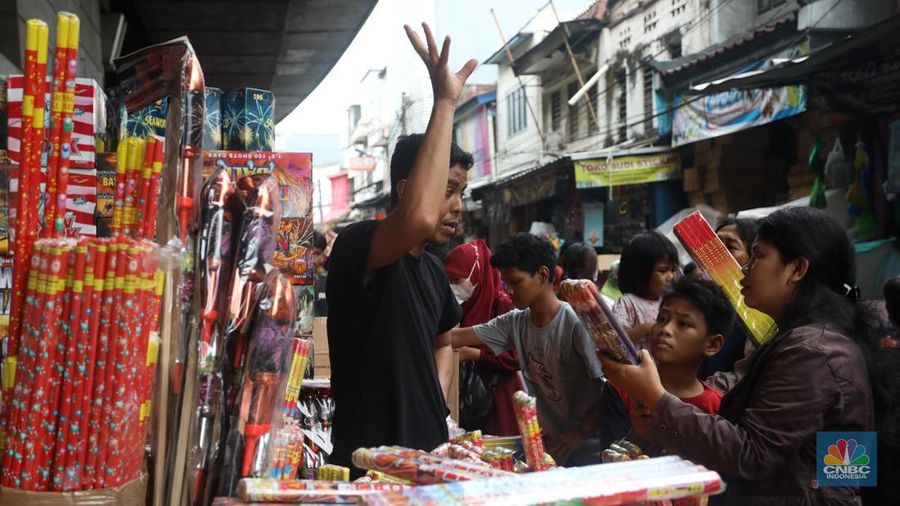 Pedagang melayani pembeli kembang api yang dijual di kawasan pasar Asemka, Jakarta Barat, Jumat (30/12/2022). Jelang perayaan tahun baru penjualan kembang api meningkat. Kembang api berbagai jenis itu dijual dengan harga beragam. (CNBC Indonesia/Andrean Kristianto)