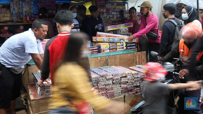 Pedagang melayani pembeli kembang api yang dijual di kawasan pasar Asemka, Jakarta Barat, Jumat (30/12/2022). Jelang perayaan tahun baru penjualan kembang api meningkat. Kembang api berbagai jenis itu dijual dengan harga beragam. (CNBC Indonesia/Andrean Kristianto)