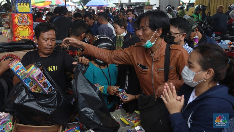 Pedagang melayani pembeli kembang api yang dijual di kawasan pasar Asemka, Jakarta Barat, Jumat (30/12/2022). Jelang perayaan tahun baru penjualan kembang api meningkat. Kembang api berbagai jenis itu dijual dengan harga beragam. (CNBC Indonesia/Andrean Kristianto)