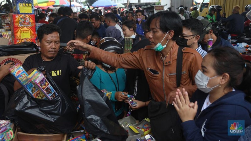 Pedagang melayani pembeli kembang api yang dijual di kawasan pasar Asemka, Jakarta Barat, Jumat (30/12/2022). Jelang perayaan tahun baru penjualan kembang api meningkat. Kembang api berbagai jenis itu dijual dengan harga beragam. (CNBC Indonesia/Andrean Kristianto)