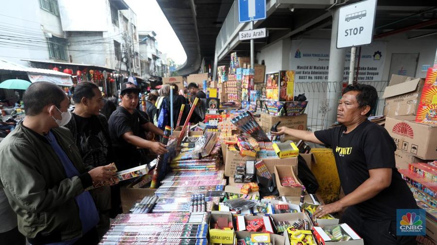 Pedagang melayani pembeli kembang api yang dijual di kawasan pasar Asemka, Jakarta Barat, Jumat (30/12/2022). Jelang perayaan tahun baru penjualan kembang api meningkat. Kembang api berbagai jenis itu dijual dengan harga beragam. (CNBC Indonesia/Andrean Kristianto)