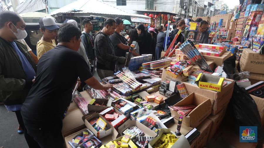 Pedagang melayani pembeli kembang api yang dijual di kawasan pasar Asemka, Jakarta Barat, Jumat (30/12/2022). Jelang perayaan tahun baru penjualan kembang api meningkat. Kembang api berbagai jenis itu dijual dengan harga beragam. (CNBC Indonesia/Andrean Kristianto)