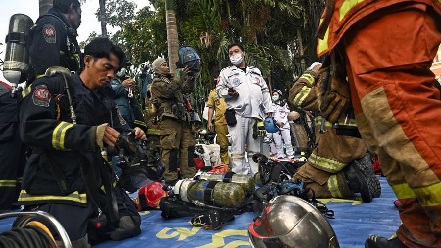 Tim paramedis berjalan melalui bagian kasino hotel Grand Diamond City yang terbakar setelah kebakaran besar di kompleks tersebut, di Poipet di provinsi Banteay Meanchey pada 30 Desember 2022. - Setidaknya 19 orang tewas dan banyak lainnya dikhawatirkan tewas dalam kebakaran di kasino Kamboja, kata para pejabat, dengan seorang penyelamat menggambarkan bagaimana para korban melemparkan diri mereka dari langkan dalam upaya putus asa untuk melarikan diri dari api. (TANG CHHIN SOTHY/AFP via Getty Images)