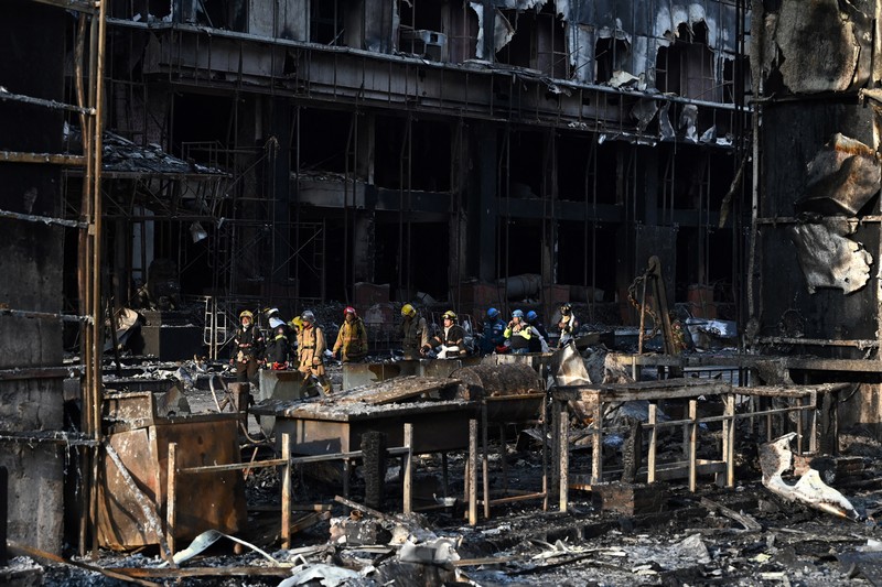 Tim paramedis berjalan melalui bagian kasino hotel Grand Diamond City yang terbakar setelah kebakaran besar di kompleks tersebut, di Poipet di provinsi Banteay Meanchey pada 30 Desember 2022. Tim paramedis berjalan melalui bagian kasino hotel Grand Diamond City yang terbakar setelah kebakaran besar di kompleks tersebut, di Poipet di provinsi Banteay Meanchey pada 30 Desember 2022. - Setidaknya 19 orang tewas dan banyak lainnya dikhawatirkan tewas dalam kebakaran di kasino Kamboja, kata para pejabat, dengan seorang penyelamat menggambarkan bagaimana para korban melemparkan diri mereka dari langkan dalam upaya putus asa untuk melarikan diri dari api. (TANG CHHIN SOTHY/AFP via Getty Images)
