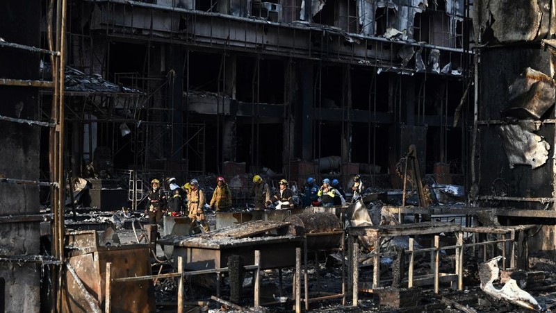 Tim paramedis berjalan melalui bagian kasino hotel Grand Diamond City yang terbakar setelah kebakaran besar di kompleks tersebut, di Poipet di provinsi Banteay Meanchey pada 30 Desember 2022. - Setidaknya 19 orang tewas dan banyak lainnya dikhawatirkan tewas dalam kebakaran di kasino Kamboja, kata para pejabat, dengan seorang penyelamat menggambarkan bagaimana para korban melemparkan diri mereka dari langkan dalam upaya putus asa untuk melarikan diri dari api. (TANG CHHIN SOTHY/AFP via Getty Images)