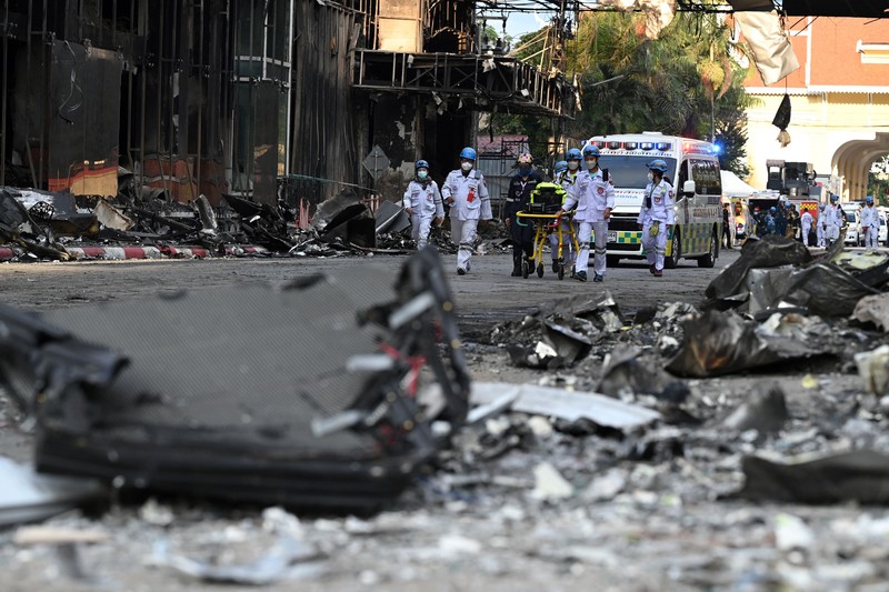 Tim paramedis berjalan melalui bagian kasino hotel Grand Diamond City yang terbakar setelah kebakaran besar di kompleks tersebut, di Poipet di provinsi Banteay Meanchey pada 30 Desember 2022. Tim paramedis berjalan melalui bagian kasino hotel Grand Diamond City yang terbakar setelah kebakaran besar di kompleks tersebut, di Poipet di provinsi Banteay Meanchey pada 30 Desember 2022. - Setidaknya 19 orang tewas dan banyak lainnya dikhawatirkan tewas dalam kebakaran di kasino Kamboja, kata para pejabat, dengan seorang penyelamat menggambarkan bagaimana para korban melemparkan diri mereka dari langkan dalam upaya putus asa untuk melarikan diri dari api. (TANG CHHIN SOTHY/AFP via Getty Images)