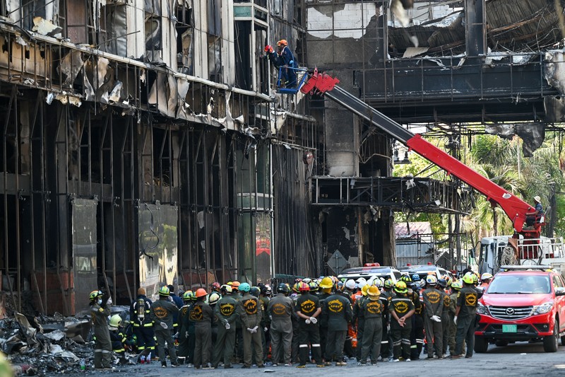 Tim paramedis berjalan melalui bagian kasino hotel Grand Diamond City yang terbakar setelah kebakaran besar di kompleks tersebut, di Poipet di provinsi Banteay Meanchey pada 30 Desember 2022. Tim paramedis berjalan melalui bagian kasino hotel Grand Diamond City yang terbakar setelah kebakaran besar di kompleks tersebut, di Poipet di provinsi Banteay Meanchey pada 30 Desember 2022. - Setidaknya 19 orang tewas dan banyak lainnya dikhawatirkan tewas dalam kebakaran di kasino Kamboja, kata para pejabat, dengan seorang penyelamat menggambarkan bagaimana para korban melemparkan diri mereka dari langkan dalam upaya putus asa untuk melarikan diri dari api. (TANG CHHIN SOTHY/AFP via Getty Images)