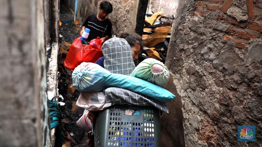 Warga membawa barang yang masih bisa diselamatkan di pemukiman yang terbakar di Jalan Bangka Buntu, Mampang Prapatan, Jakarta, Jumat (30/12/2022). (վ/Muhammad Sabki)
