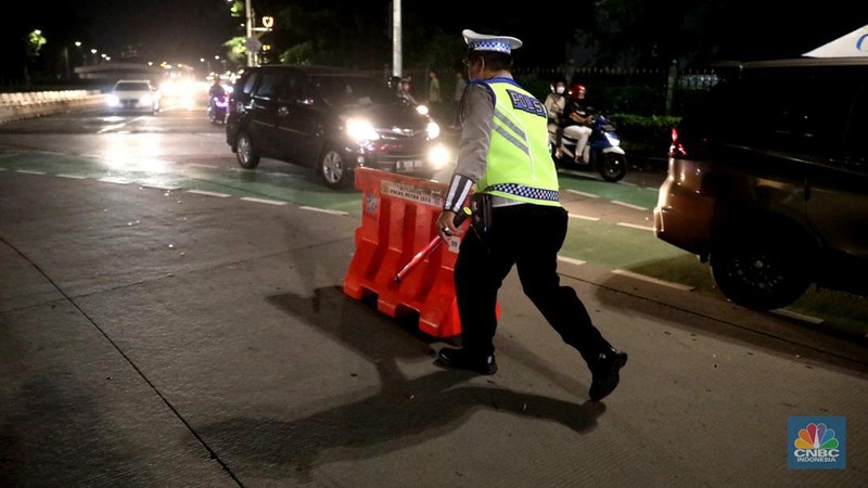 Petugas Polisi lalu lintas bersama dishub memasang pembatas lalu lintas saat penutupan jalan untuk car free night di Bundaran Senayan, Jakarta, Sabtu, 31/12. (CNBC Indonesia / Muhammad Sabki)