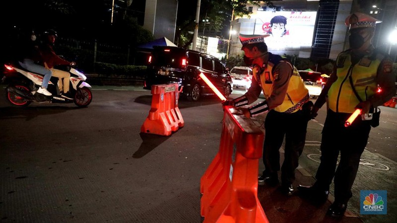Petugas Polisi lalu lintas bersama dishub memasang pembatas lalu lintas saat penutupan jalan untuk car free night di Bundaran Senayan, Jakarta, Sabtu, 31/12. (CNBC Indonesia / Muhammad Sabki)