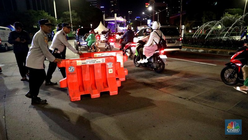 Petugas Polisi lalu lintas bersama dishub memasang pembatas lalu lintas saat penutupan jalan untuk car free night di Bundaran Senayan, Jakarta, Sabtu, 31/12. (CNBC Indonesia / Muhammad Sabki)