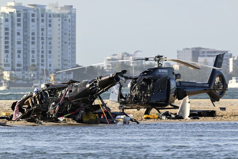 Dua helikopter bertabrakan menewaskan beberapa penumpang dan melukai beberapa lainnya dalam kecelakaan yang menarik bantuan darurat dari pengunjung pantai yang menikmati air selama musim panas selatan. Pekerja darurat memeriksa helikopter di lokasi tabrakan dekat Seaworld, di Gold Coast, Australia, Senin, 2 Januari 2023. Dua helikopter bertabrakan menewaskan beberapa penumpang dan melukai beberapa lainnya dalam kecelakaan yang menarik bantuan darurat dari pengunjung pantai yang menikmati air selama musim panas selatan. (Dave Hunt/AAP Image via AP)