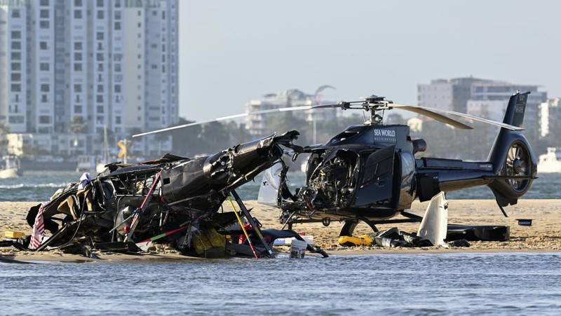 Pekerja darurat memeriksa helikopter di lokasi tabrakan dekat Seaworld, di Gold Coast, Australia, Senin, 2 Januari 2023. Dua helikopter bertabrakan menewaskan beberapa penumpang dan melukai beberapa lainnya dalam kecelakaan yang menarik bantuan darurat dari pengunjung pantai yang menikmati air selama musim panas selatan. (Dave Hunt/AAP Image via AP)
