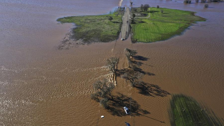 Three vehicles are submerged on Dillard Road west of Highway 99 in south Sacramento County in Wilton, Calif., Sunday, Jan. 1, 2023, after heavy rains on New Year's Eve produced levee breaks. Saturday's system was warmer and wetter, while storms this week will be colder, said Hannah Chandler-Cooley, a meteorologist at the National Weather Service in Sacramento. The Sacramento region could receive a total of 4 to 5 inches (10 to 13 centimeters) of rain over the week, Chandler-Cooley said. (Hector Amezcua/The Sacramento Bee via AP)