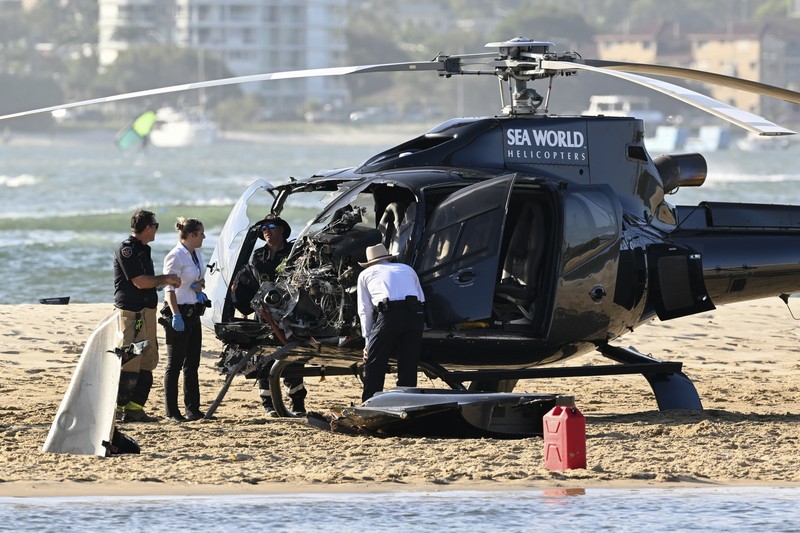 Dua helikopter bertabrakan menewaskan beberapa penumpang dan melukai beberapa lainnya dalam kecelakaan yang menarik bantuan darurat dari pengunjung pantai yang menikmati air selama musim panas selatan. Pekerja darurat memeriksa helikopter di lokasi tabrakan dekat Seaworld, di Gold Coast, Australia, Senin, 2 Januari 2023. Dua helikopter bertabrakan menewaskan beberapa penumpang dan melukai beberapa lainnya dalam kecelakaan yang menarik bantuan darurat dari pengunjung pantai yang menikmati air selama musim panas selatan. (Dave Hunt/AAP Image via AP)