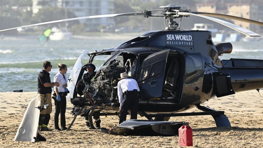 Pekerja darurat memeriksa helikopter di lokasi tabrakan dekat Seaworld, di Gold Coast, Australia, Senin, 2 Januari 2023. Dua helikopter bertabrakan menewaskan beberapa penumpang dan melukai beberapa lainnya dalam kecelakaan yang menarik bantuan darurat dari pengunjung pantai yang menikmati air selama musim panas selatan. (Dave Hunt/AAP Image via AP)