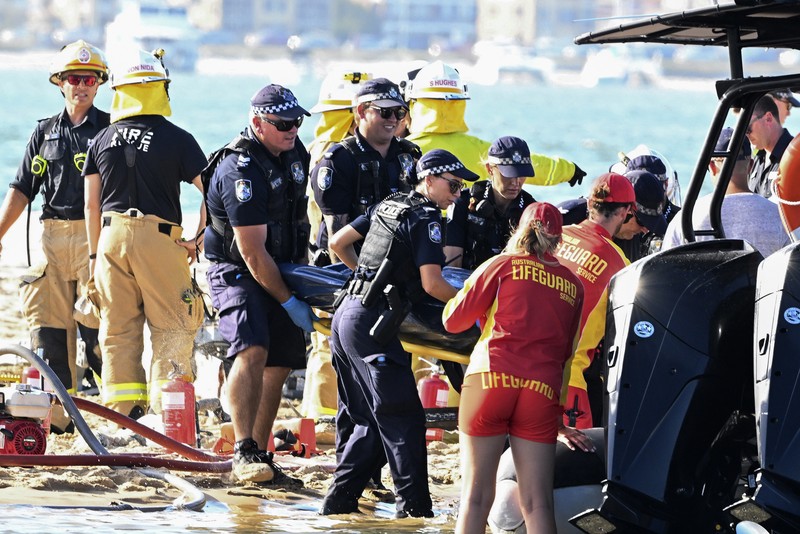 Pekerja darurat memeriksa helikopter di lokasi tabrakan dekat Seaworld, di Gold Coast, Australia, Senin, 2 Januari 2023. Dua helikopter bertabrakan menewaskan beberapa penumpang dan melukai beberapa lainnya dalam kecelakaan yang menarik bantuan darurat dari pengunjung pantai yang menikmati air selama musim panas selatan. (Dave Hunt/AAP Image via AP)