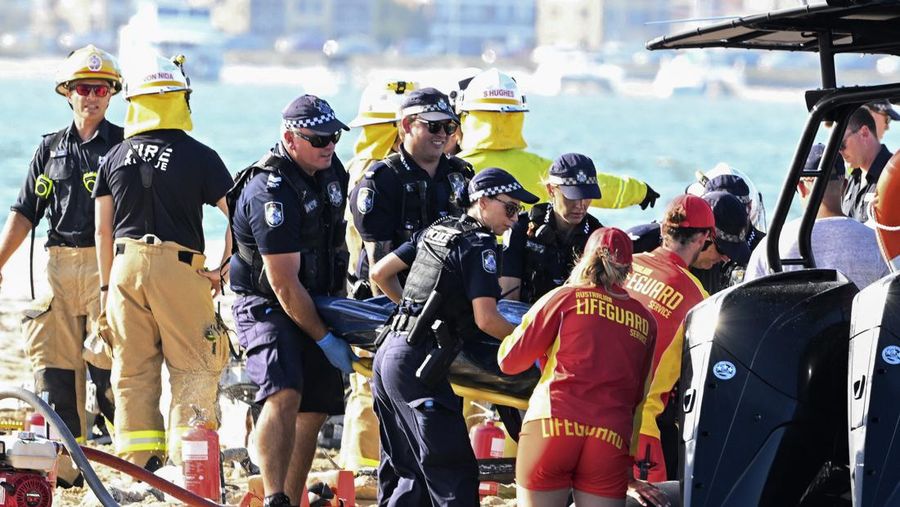 Pekerja darurat memeriksa helikopter di lokasi tabrakan dekat Seaworld, di Gold Coast, Australia, Senin, 2 Januari 2023. Dua helikopter bertabrakan menewaskan beberapa penumpang dan melukai beberapa lainnya dalam kecelakaan yang menarik bantuan darurat dari pengunjung pantai yang menikmati air selama musim panas selatan. (Dave Hunt/AAP Image via AP)