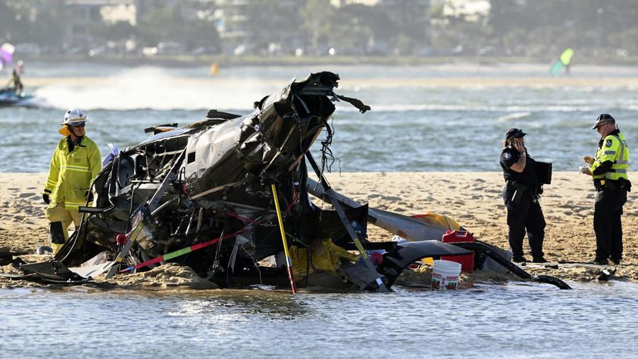 Dua helikopter bertabrakan menewaskan beberapa penumpang dan melukai beberapa lainnya dalam kecelakaan yang menarik bantuan darurat dari pengunjung pantai yang menikmati air selama musim panas selatan. Pekerja darurat memeriksa helikopter di tempat kejadian tabrakan dekat Seaworld, di Gold Coast, Australia, Senin, 2 Januari 2023. Dua helikopter bertabrakan menewaskan beberapa penumpang dan melukai beberapa lainnya dalam kecelakaan yang menarik bantuan darurat dari pengunjung pantai yang menikmati air selama musim panas selatan. (Dave Hunt/AAP Image via AP)