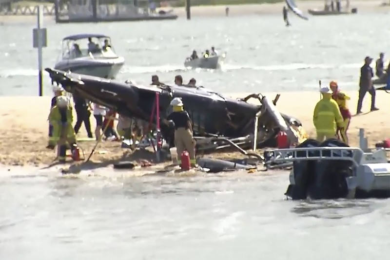 Pekerja darurat memeriksa helikopter di lokasi tabrakan dekat Seaworld, di Gold Coast, Australia, Senin, 2 Januari 2023. Dua helikopter bertabrakan menewaskan beberapa penumpang dan melukai beberapa lainnya dalam kecelakaan yang menarik bantuan darurat dari pengunjung pantai yang menikmati air selama musim panas selatan. (Dave Hunt/AAP Image via AP)
