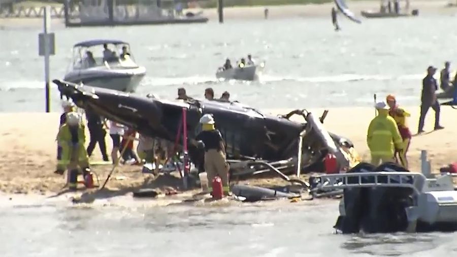 Pekerja darurat memeriksa helikopter di lokasi tabrakan dekat Seaworld, di Gold Coast, Australia, Senin, 2 Januari 2023. Dua helikopter bertabrakan menewaskan beberapa penumpang dan melukai beberapa lainnya dalam kecelakaan yang menarik bantuan darurat dari pengunjung pantai yang menikmati air selama musim panas selatan. (Dave Hunt/AAP Image via AP)