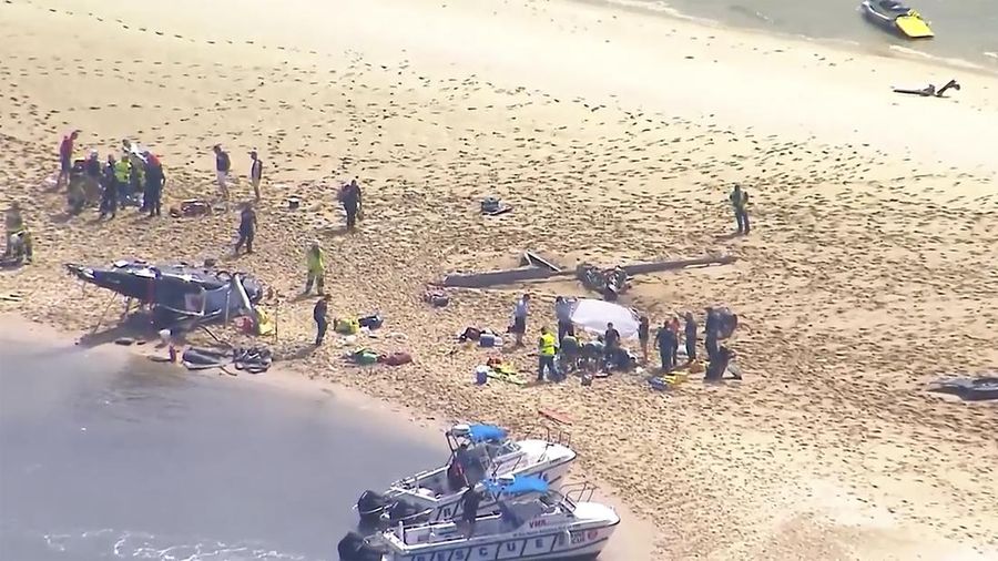 Pekerja darurat memeriksa helikopter di lokasi tabrakan dekat Seaworld, di Gold Coast, Australia, Senin, 2 Januari 2023. Dua helikopter bertabrakan menewaskan beberapa penumpang dan melukai beberapa lainnya dalam kecelakaan yang menarik bantuan darurat dari pengunjung pantai yang menikmati air selama musim panas selatan. (Dave Hunt/AAP Image via AP)