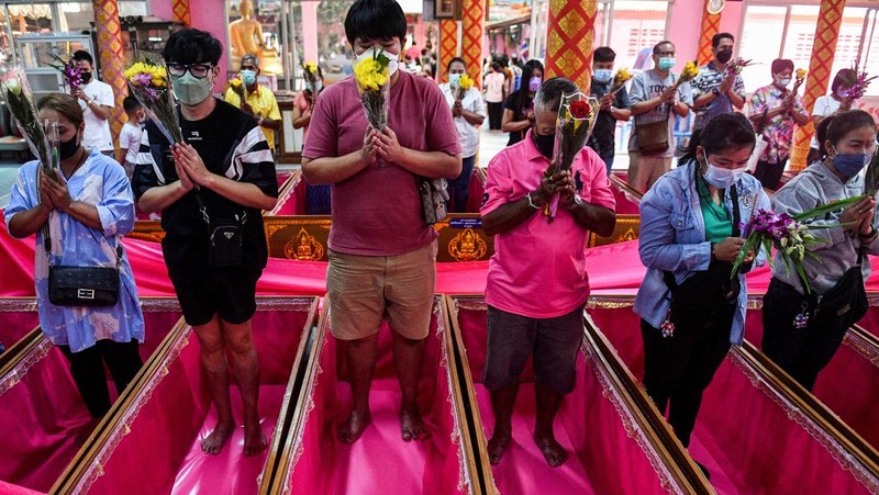 Umat berbaring dan berdoa di dalam peti mati untuk menghilangkan nasib buruk dan terlahir kembali untuk awal yang baru di Tahun Baru di sebuah kuil di Nonthaburi, di pinggiran Bangkok, Thailand 2 Januari 2023. (REUTERS/Chalinee Thirasupa)