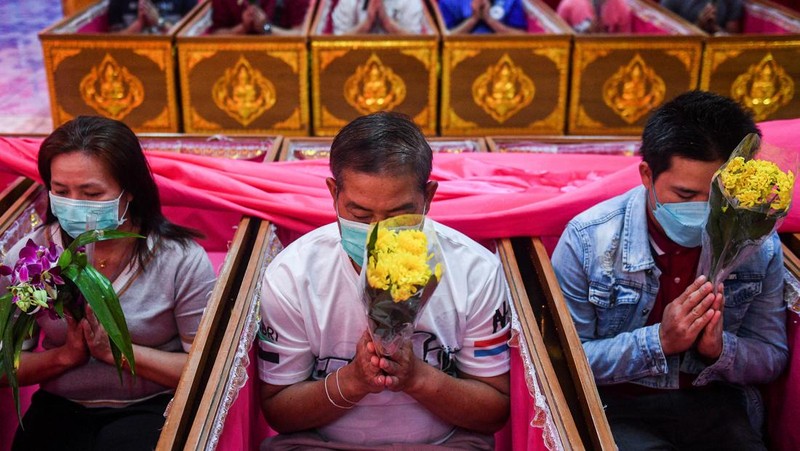 Umat berbaring dan berdoa di dalam peti mati untuk menghilangkan nasib buruk dan terlahir kembali untuk awal yang baru di Tahun Baru di sebuah kuil di Nonthaburi, di pinggiran Bangkok, Thailand 2 Januari 2023. (REUTERS/Chalinee Thirasupa)