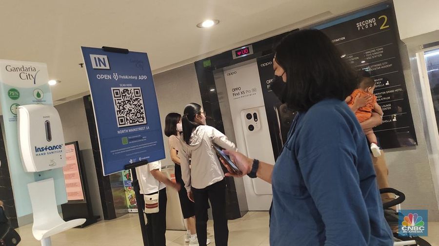 Pengunjung memindai kode batang (scan barcode) aplikasi peduli lindungi saat memasuki Gandaria City, Jakarta, Senin (2/1/2023). Presiden Joko Widodo (Jokowi) resmi mencabut Pemberlakuan Pembatasan Kegiatan Masyarakat (PPKM) pada Jumat (30/12/2022). (CNBC Indonesia/Andrean Kristianto)