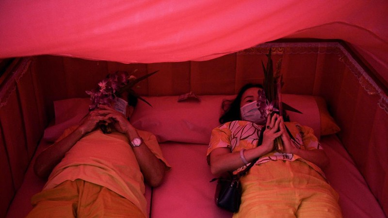 Umat berbaring dan berdoa di dalam peti mati untuk menghilangkan nasib buruk dan terlahir kembali untuk awal yang baru di Tahun Baru di sebuah kuil di Nonthaburi, di pinggiran Bangkok, Thailand 2 Januari 2023. (REUTERS/Chalinee Thirasupa)